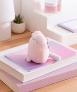 Side view of the pink fluffy bag charm. The striped tail can be seen extending off the back bottom of the keychain.