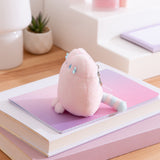 Side view of the pink fluffy bag charm. The striped tail can be seen extending off the back bottom of the keychain.