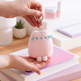 Model holds keychain and bottom of bag charm to show size and scale of the pink fluffy Pusheen keychain. 