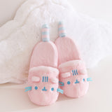 Pair of pink cat-shaped slippers with blue face accents including three stripes between the 3D triangular ears. 