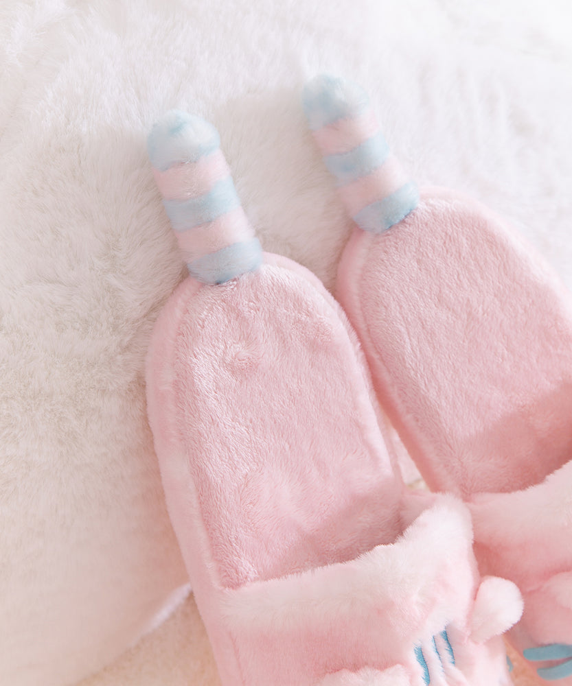 Close-up of the light pink and blue striped tails that extend off the back of the plush Pusheen slippers.