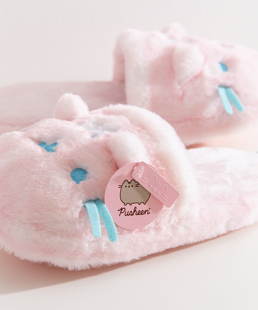 Close-up of the pink Pusheen Label logo tag attached to the 3D ear on the plush slippers.