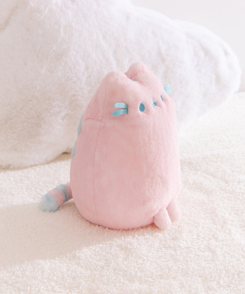Side quarter view of the Pink Dreamsheen Plush. The striped tail can be seen extending off the back of the plush in this image.