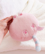 Pink plush toy with embroidered pink paw prints held by a hand on a soft white background.