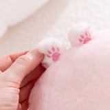 Close-up of a hand holding a pink plush toy with tiny pink paw prints on a light background.