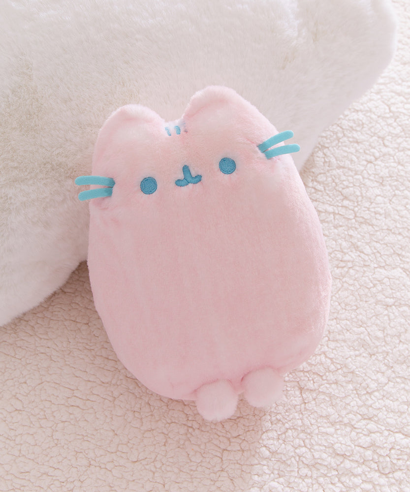 Pink plush toy with blue accents on a soft beige background.