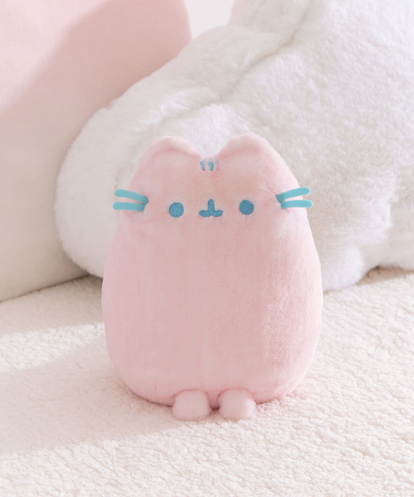 Front view of the Pink Dreamsheen Plush. Pusheen the Cat's embroidered three head stripes, eyes, mouth, and 3D whiskers are a light blue color. 