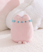 Front view of the Pink Dreamsheen Plush. Pusheen the Cat's embroidered three head stripes, eyes, mouth, and 3D whiskers are a light blue color. 