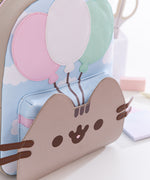 Close-up of the smiling cat face and balloons trio on the very front of the 15th Anniversary Backpack. Pusheen's face hides the access to the front pocket. 