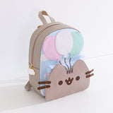 Pusheen 15th Anniversary Backpack sits on a white desktop. The grey backpack has Pusheen's 3D face on the front with a blue sky and clouds pattern above. 