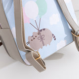 Close-up of the back graphic on the backpack that shows Pusheen the Cat floating through puffy clouds attached to pink, white, and mint green balloons.