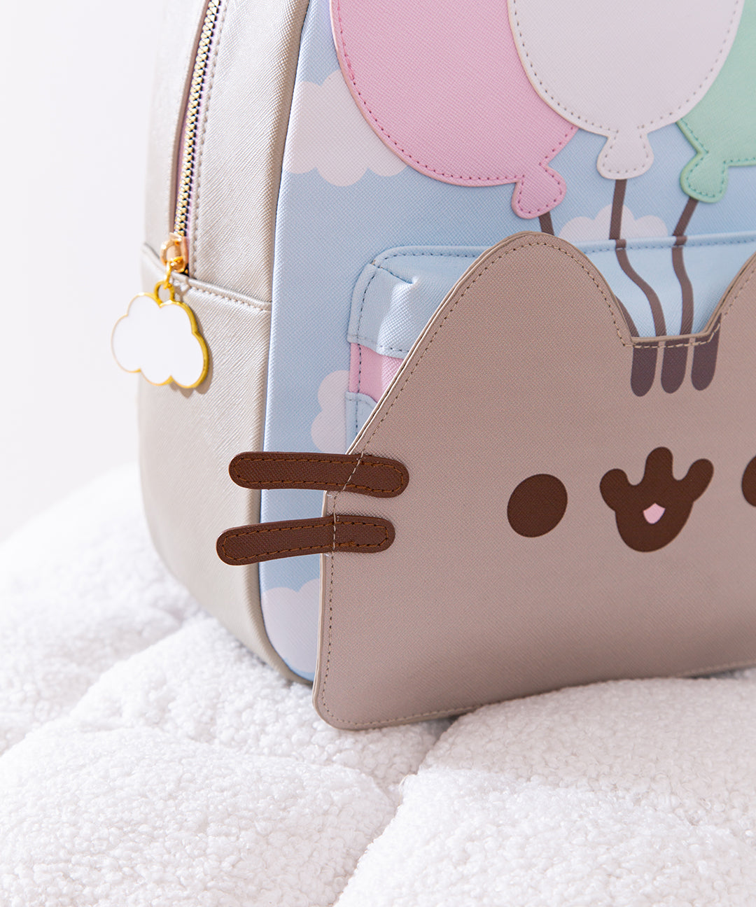 Close-up of Pusheen's smiling face on the Balloons backpack. Pusheen's brown whiskers are 3D and stick out to the sides of the backpack. 
