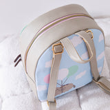 Top aerial view of the backpack and cloud motif back graphic. The grey backpack has a pink and gold zipper. 
