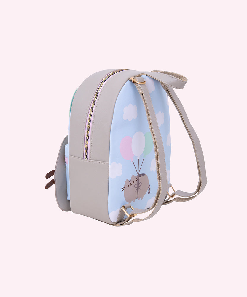 Side and back view of the backpack. The pack has gray adjustable straps with golden hardware. The back of the pack features a graphic of Pusheen the Cat floating through a cloudy sky. 