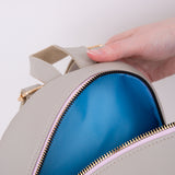 Model holds open top zipper of the cat backpack to show blue interior.