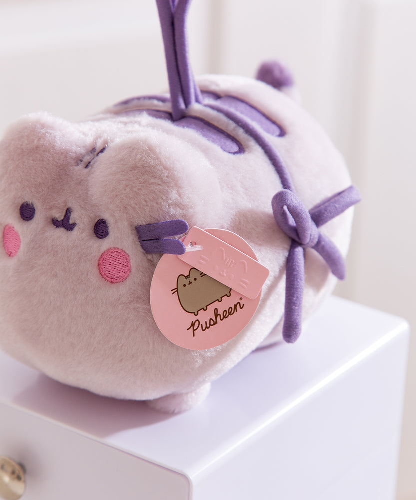 Close-up of the pink Pusheen Label logo tags attached near the face of the blushing cat toy plush.