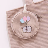 Pin of Pusheen dangling from three balloons. The silver outlined pin is attached to a corduroy bag.