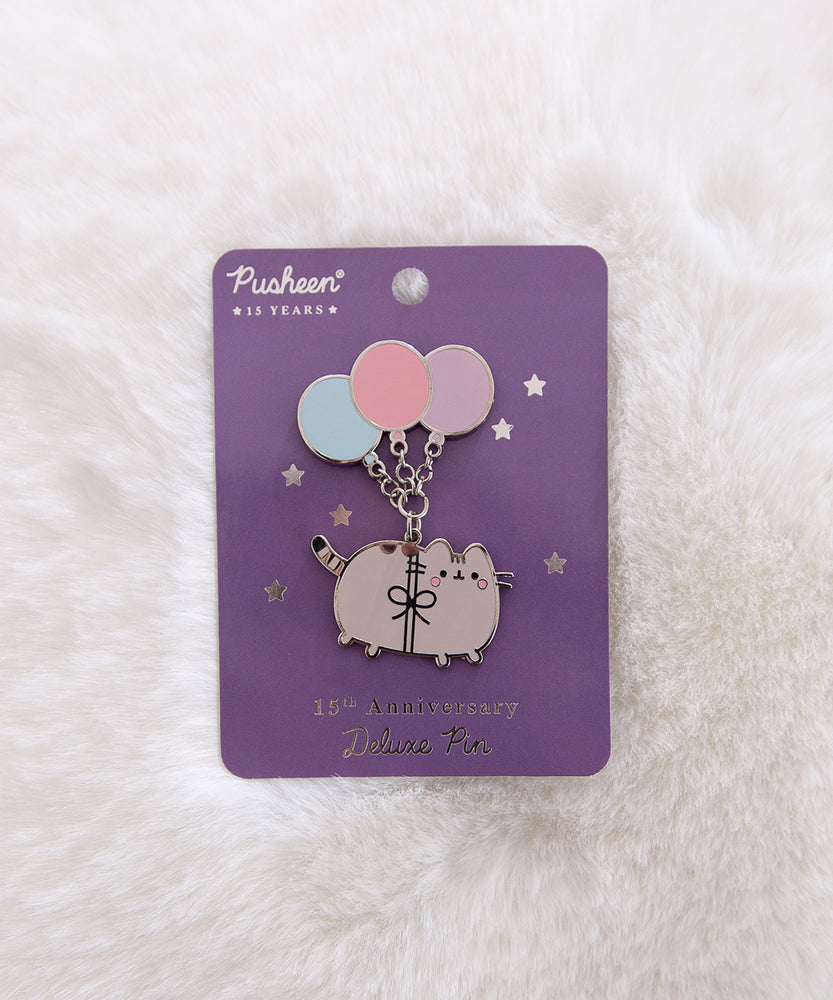 Pusheen pin with balloons on a purple card against a white fur background.
