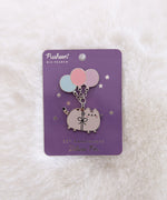 Pusheen pin with balloons on a purple card against a white fur background.