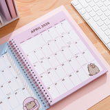 Full month calendar view for April 2026 in the Pusheen 2025-2026 16-Month Planner. In the right bottom corner of the page is a graphic of Pusheen the Cat holding a pink glazed donut. 