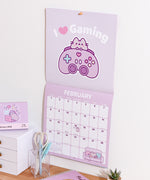 Purple gaming-themed calendar with 
February 2026 page spread showing. The top half shows a graphic of Pusheen with a purple gaming controller and the phrase 'I ❤️ Gaming'.