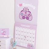 Purple gaming-themed calendar with 
February 2026 page spread showing. The top half shows a graphic of Pusheen with a purple gaming controller and the phrase 'I ❤️ Gaming'.