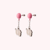 Pair of silver Pusheen dangle earrings angled to show the silver earring posts and backers that are attached to the pink balloons that Pusheen hangs from.