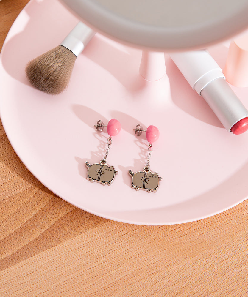 Pusheen Balloon Dangle Earrings on a jewelry dish. The studs with balloons are angled to the side to show the post and backing. 