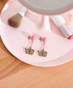 Pusheen Balloon Dangle Earrings on a jewelry dish. The studs with balloons are angled to the side to show the post and backing. 
