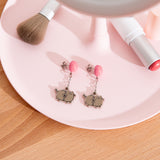 Pusheen Balloon Dangle Earrings on a jewelry dish. The studs with balloons are angled to the side to show the post and backing. 