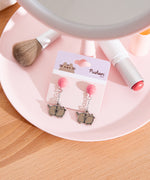 Balloon earrings on backing card. The silver outlined earrings show a pair of Pusheen's tied to a balloon. 