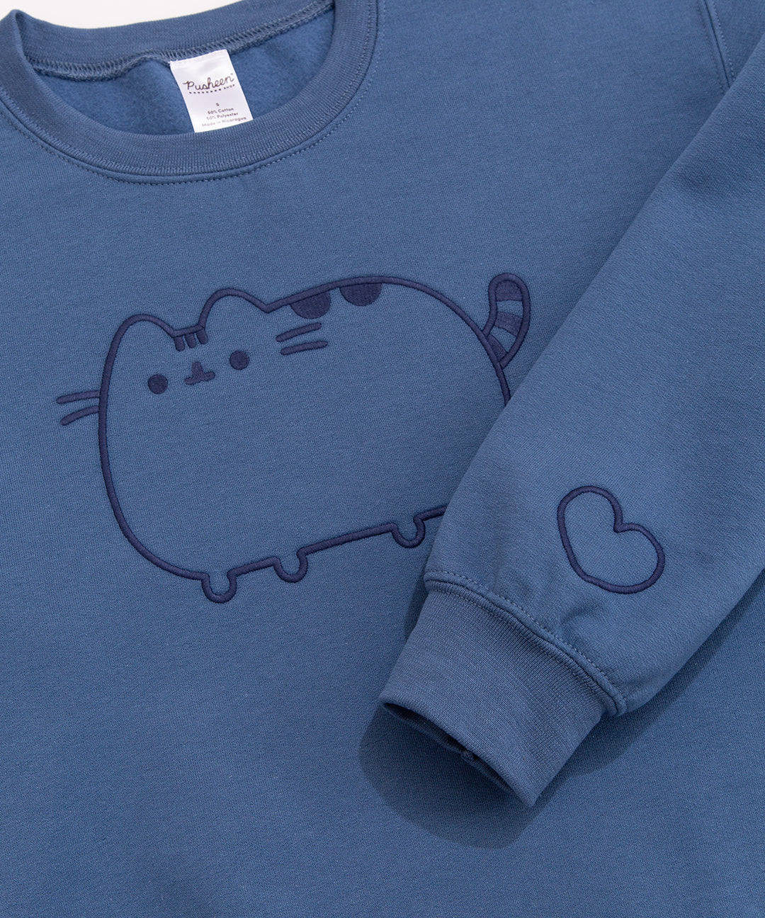Close-up of the navy blue embroidery details on the chest and sleeve of the Pusheen Blue Embroidered Unisex Sweatshirt.