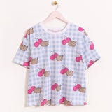 Hung on a pink hanger, the Pusheen Pajama Tee is hung to show the full length of the oversized t-shirt. The blue and white checkered tee has printed all over graphic of Pusheen and cherries. 