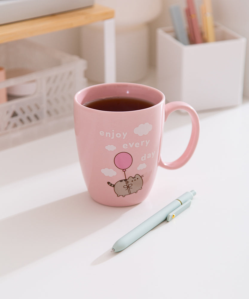 Enjoy Every Day Mug sits on a white desktop with tea inside the pink mug.