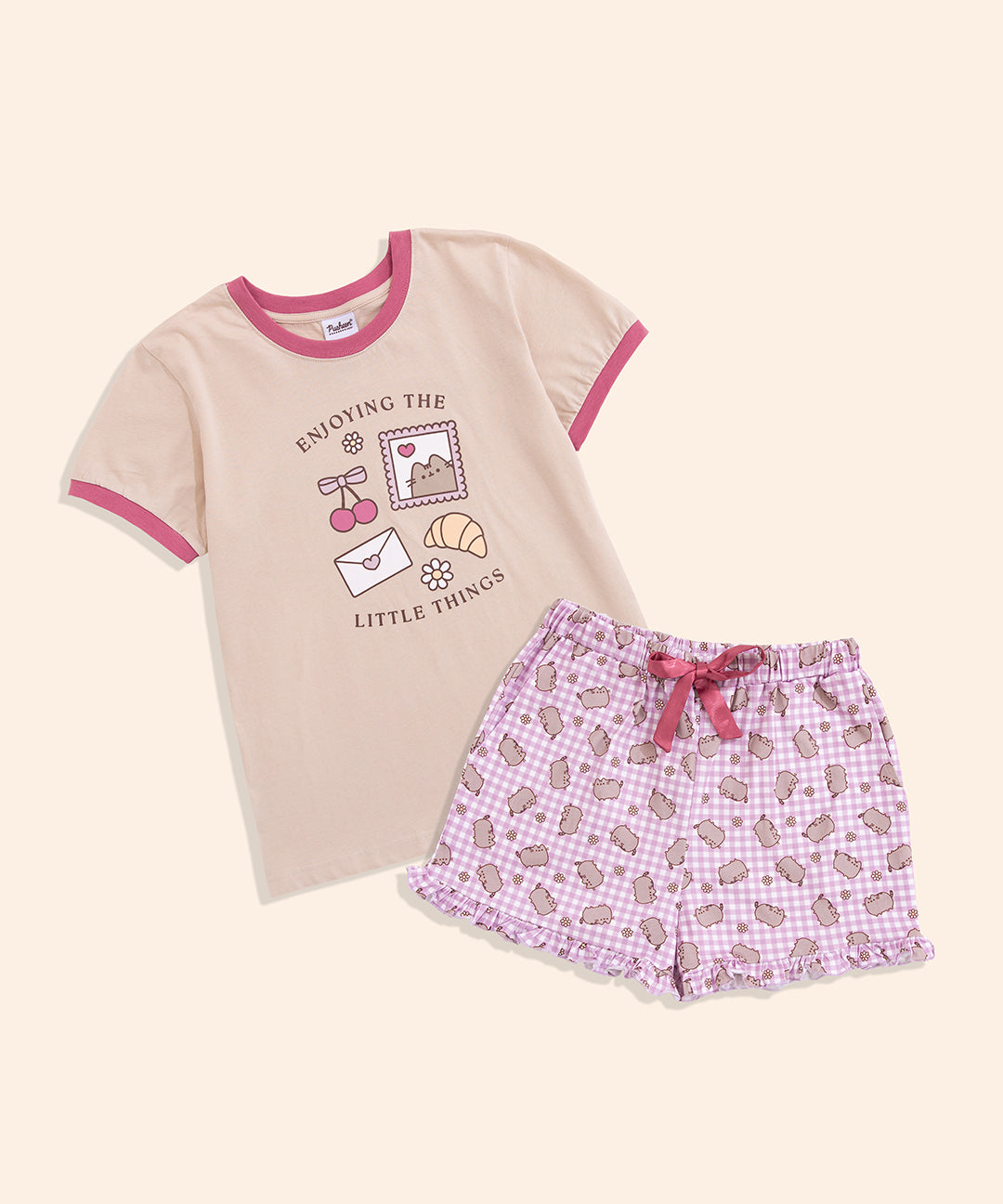 Ladies pajama set includes a beige top with pink piping details and pink gingham print shorts with a ruffle hem.