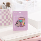 Pusheen Gamer Arcade Deluxe Pin on a purple backer card. The large pin features Pusheen the Cat playing a retro arcade game that's pink and decorated with stars,  moons, and hearts. 