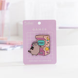 Arcade Deluxe Pin on its purple backer card. The card features a white grid pattern and says " Pusheen Shop" and "Gamer Arcade Deluxe Pin."