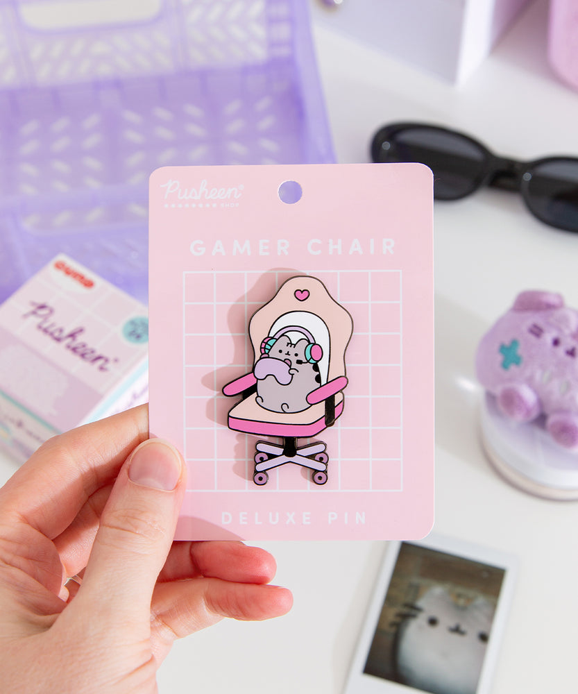 Model holds edge of backer card of the Gamer Pusheen Deluxe Pin to show the size and scale of the pin's details. 