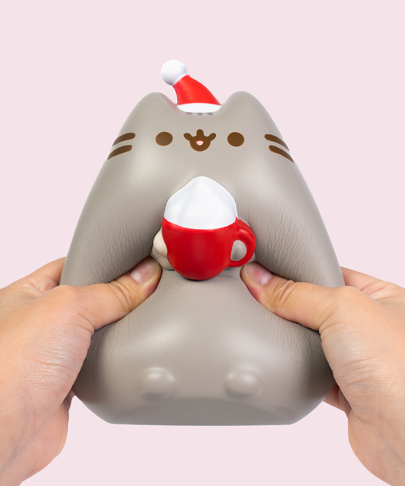 Model squishing both sides of the holiday Squishy toy that is shaped like a sitting cat.