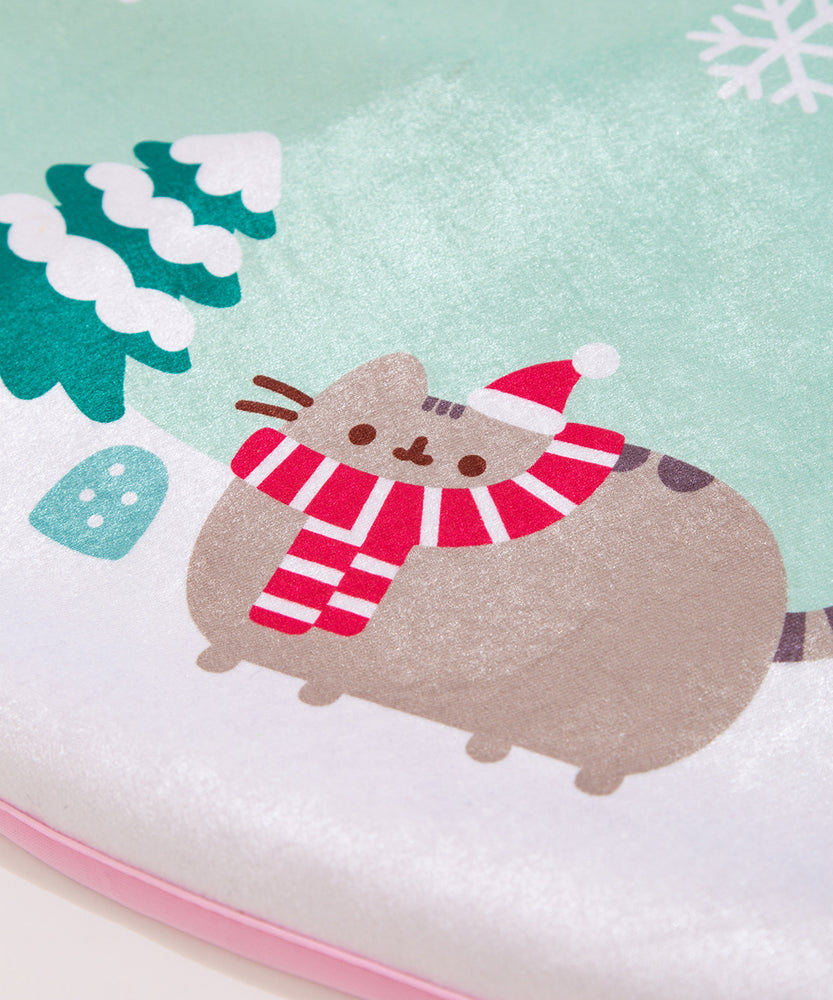Close-up of holiday Pusheen printed on the tree skirt. The brown and gray tabby cat is shown in a snowy landscape with a mint green sky.