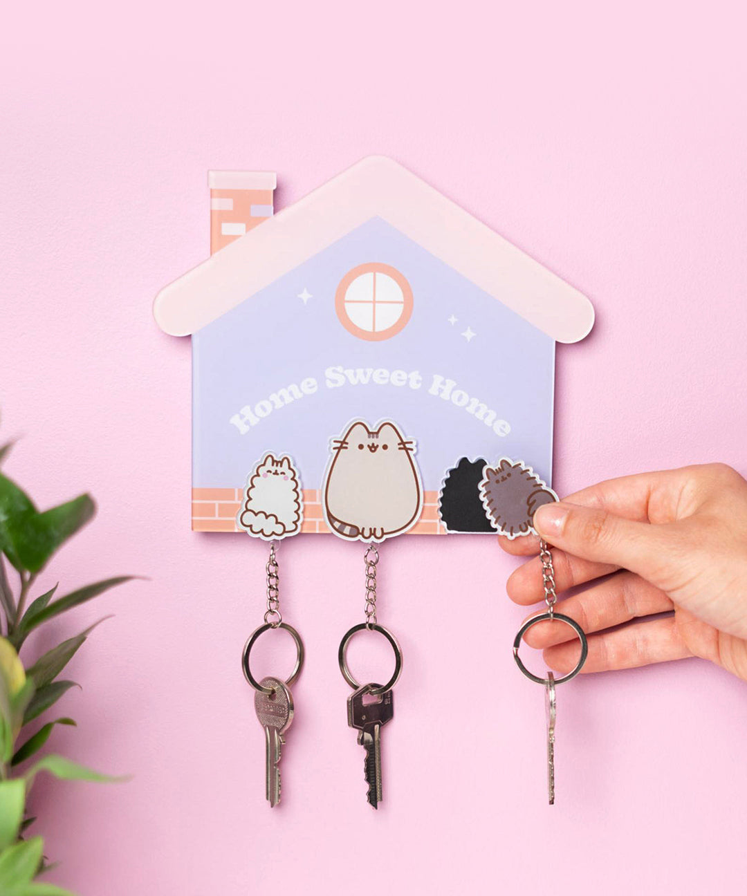 Model holds Pip keychain off to the side to show the magnetic base layer of the Magnetic Pusheen keychains.