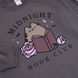 Close-up of the large graphic on the front of the Pusheen Midnight Book Club Sweatshirt. The gray tabby cat is surrounded by purple accessories.