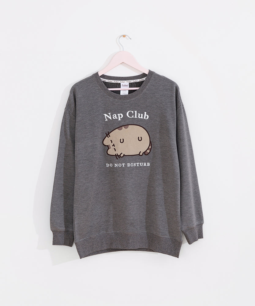 Gray sweatshirt with a sleeping cat hangs on a light pink hanger.