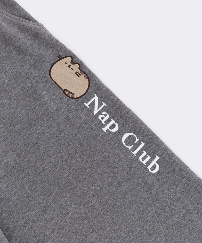 Close-up of the embroidered Pusheen graphic going down wearer's pant leg. The embroidery thread color is white and says "Nap Club" next to a graphic of a sleeping Pusheen.