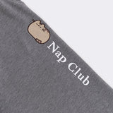 Close-up of the embroidered Pusheen graphic going down wearer's pant leg. The embroidery thread color is white and says "Nap Club" next to a graphic of a sleeping Pusheen.