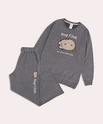 The Pusheen Nap Club Loungewear Set lies on a light background. The set includes a sweatshirt with an embroidered cat face on the front.  The set also includes gray pants that are folded in this image. 