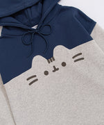 Front view of the Pusheen Navy Relaxed-Fit Character Hoodie lying on a white surface. The two-toned sweatshirt has a navy blue hoodie and chest coloring while the sleeves and bottom of the sweatshirt are light heather gray. 