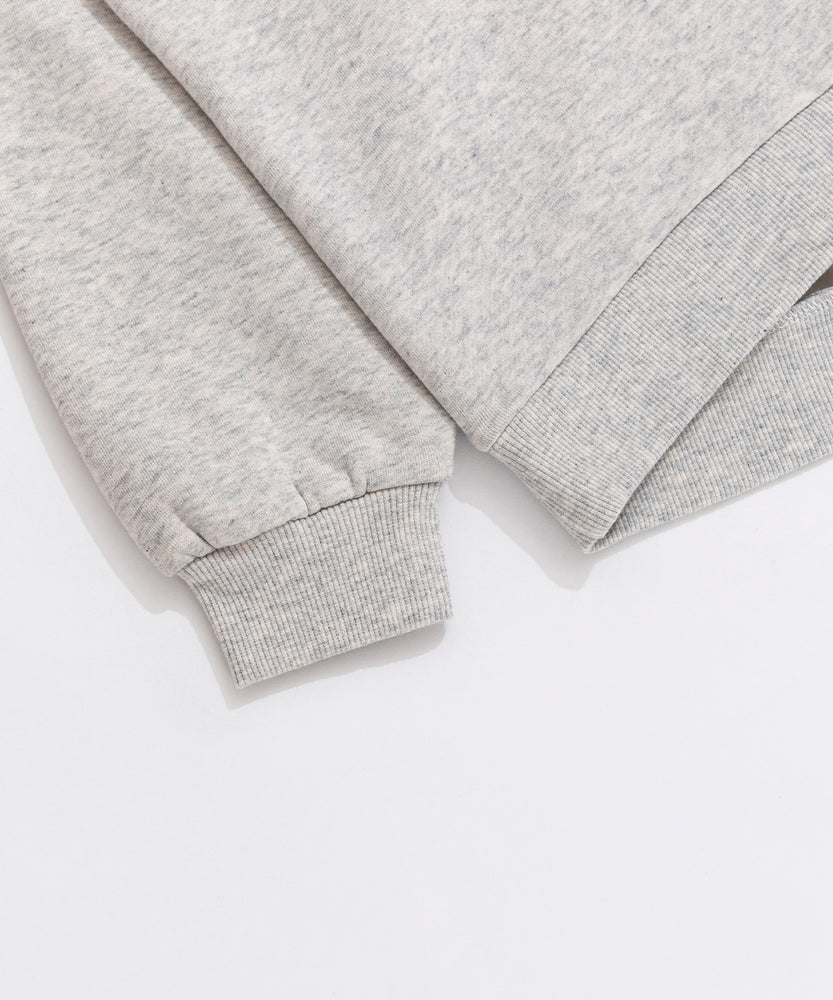 A close-up view of the cuff and hem of the Pusheen Sweatshirt. The light gray sweatshirt has tapered, ribbed detailing on the cuff and hem of the hoodie. 
