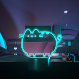 Teal neon light shaped like a cat on a desktop.