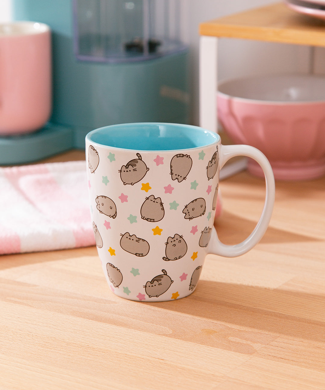 Pusheen Patterned ceramic mug is white with an all over print of Pusheen the Cat in various poses surrounded by multi-color stars.